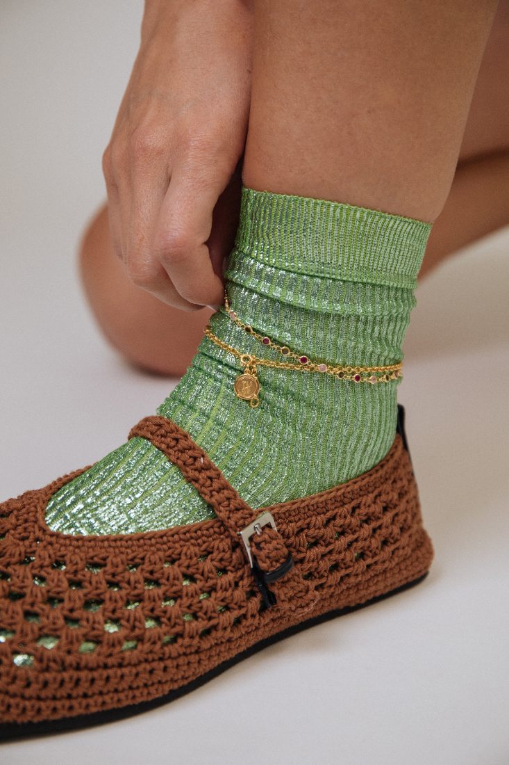 Pulseira de pé com pendente sobre meia verde